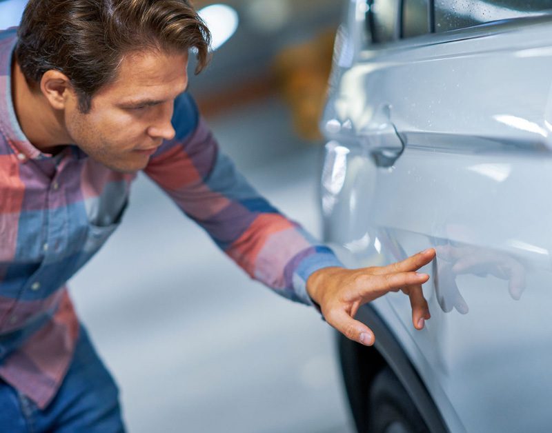 eco friendly dent repair services - man looking at his car dent